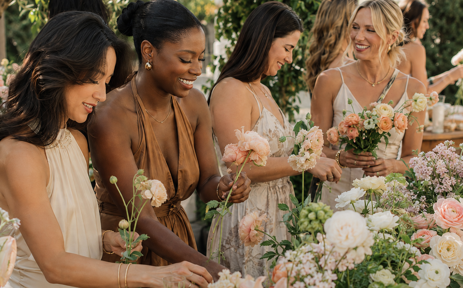 Guests arranging fresh flowers at a styled outdoor bloom bar table